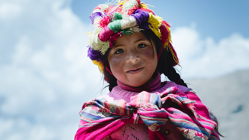 Smiling peruvian girl dressed in colourful traditional handmade outfit. October 21, 2012 - Patachancha, Cuzco, Peru