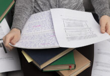 Estudiante revisando borradores y documentos de su tesis universitaria