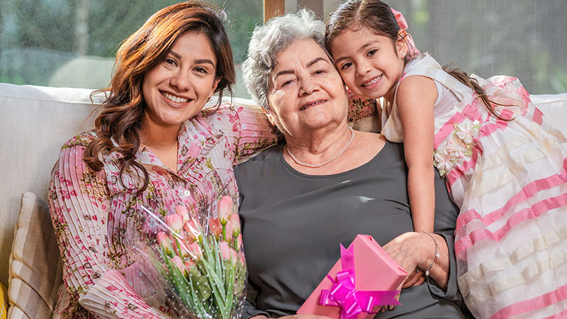 Tres generaciones celebrando el Día de la Madre con flores y regalos